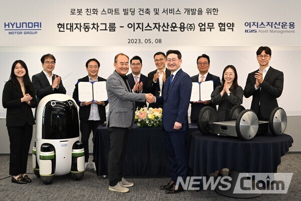 현대차·기아의 실내외 배송 로봇(왼쪽)과 모베드(MobED, 오른쪽)가 놓인 가운데 현대차∙기아 연구개발본부장 김용화 부사장(앞줄 왼쪽)과 이지스자산운용 리얼에셋부문 정석우 대표(앞줄 오른쪽)가 기념 사진을 촬영하고 있다. 사진=현대자동차그룹