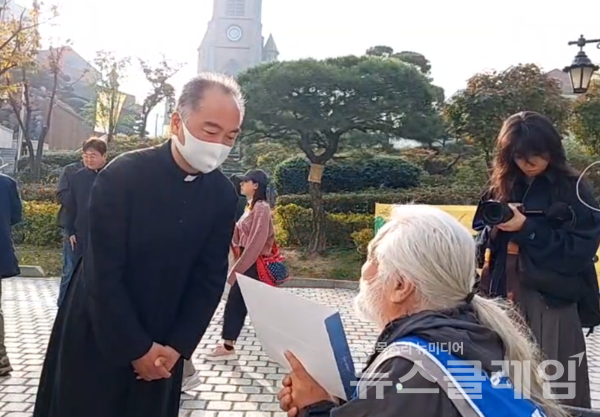 박경석 전장연 상임공동대표가 31일 오전 서울 중구 명동성당 앞에서 기자회견을 하기 전 서울대교구장 정순택 대주교 면담 요청 공문을 전달하고 있다. 사진=전장연