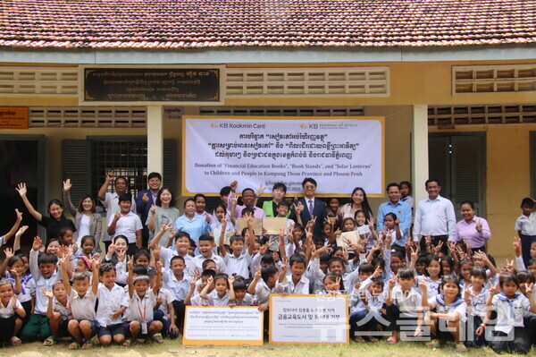 지난 7일 캄보디아 프놈펜에서 진행된 기부 물품 전달식에서 KB국민카드 현지법인 KB대한특수은행 임직원들과 운롱깐초등학교 아이들이 기념촬영을 하고 있다. KB국민카드 제공