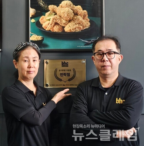 bhc치킨 민락점 신영진 점주(우측) 부부가 장기운영 현판 앞에서 포즈를 취하고 있다. bhc치킨 제공