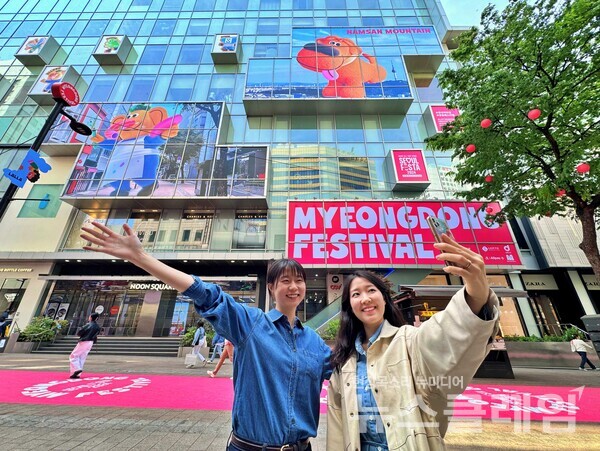 캐릭터와 서울색으로 장식된 명동길에서 사진을 촬영하는 모습. 롯데백화점 제공