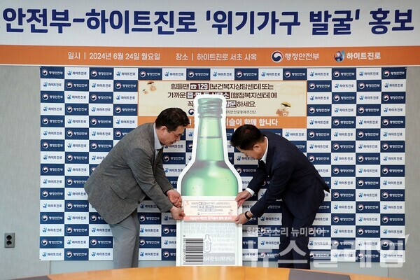 24일 오전 서울시 서초구 하이트진로 서초동사옥에서 열린 '행정안전부-하이트진로 위기가구 발굴 홍보 협약식'에 참석한 장인섭 하이트진로 전무(오른쪽)와 구본근 행정안전부 스마트복지안전공동체추진단장(왼쪽)이 홍보라벨을 부착하고 있다. 하이트진로 제공