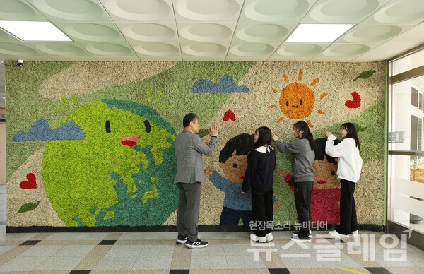 지난 4월 용인 나곡초등학교의 선생님과 아이들이 맑은학교 만들기를 통해 조성된 벽면녹화를 살펴보고 있다. 한화그룹 제공