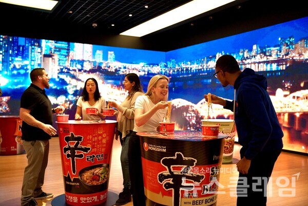 뉴욕한국문화원 청사 1층에서 한강을 주제로 한 미디어월을 배경으로 현지 소비자들이 신라면을 먹고 있다. 농심 제공