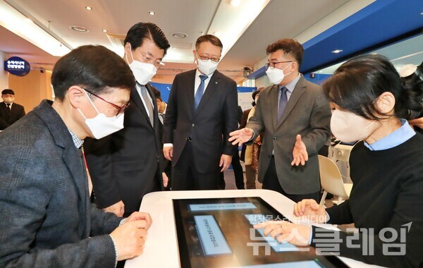 우리은행 정진완 은행장(왼쪽 세번째), 서강석 송파구청장(왼쪽 두번째)이 Woori 어르신 IT 행복배움터 송파점 개소식에 참여해 해피테이블(인지능력개선 디지털기기)에 대한 설명을 듣고 있다. 우리은행 제공