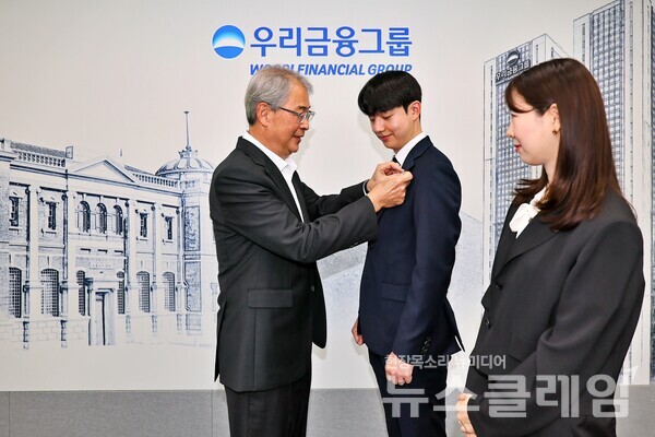 우리금융그룹 임종룡 회장이 그룹의 새 가족이 된 동양생명·ABL생명 직원에게 디지털 선도의 의미가 담긴 새로운 그룹 보조휘장을 달아주고 있다. 우리금융그룹 제공