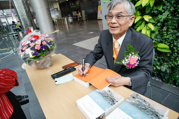 청계천 사진집 노무라 리포트에 사인을 하는 모습. 사진=최인기