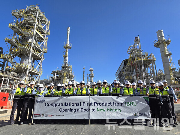 가솔린 생산을 축하하는 플래카드를 들고 이라크 바스라 정유공장 고도화설비 공사 현장 임직원들이 기념사진을 촬영하고 있다. 현대건설 제공